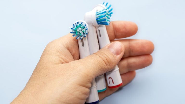 Hand holding three electric toothbrush heads