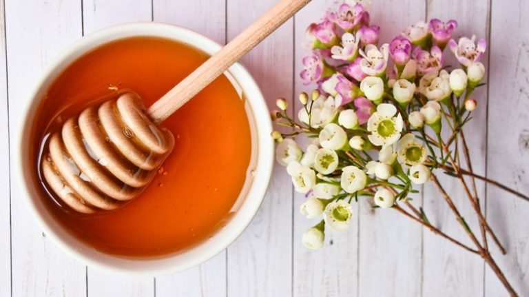 bowl of manuka honey next to flowers