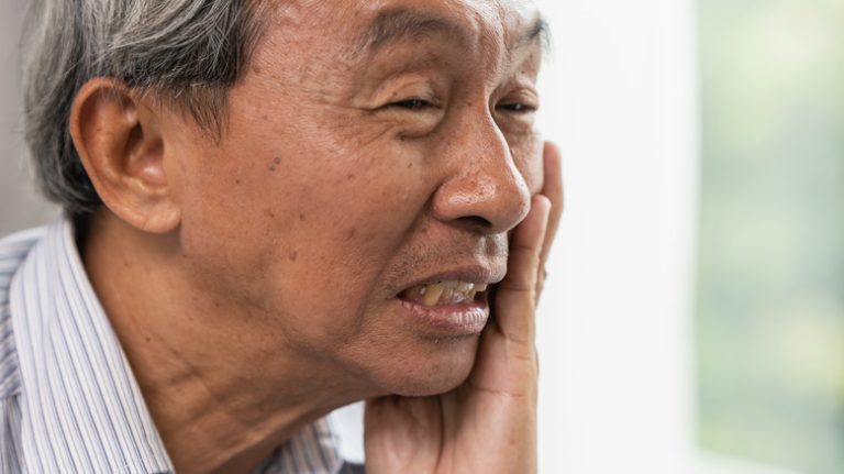 A man placing his hand on his cheek