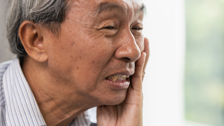 A man placing his hand on his cheek