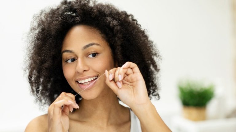 Smiling woman flossing teeth