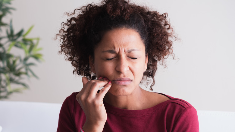 Wincing woman touching mouth in pain