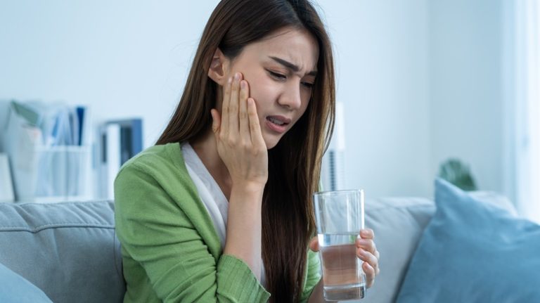 Woman touching sore mouth