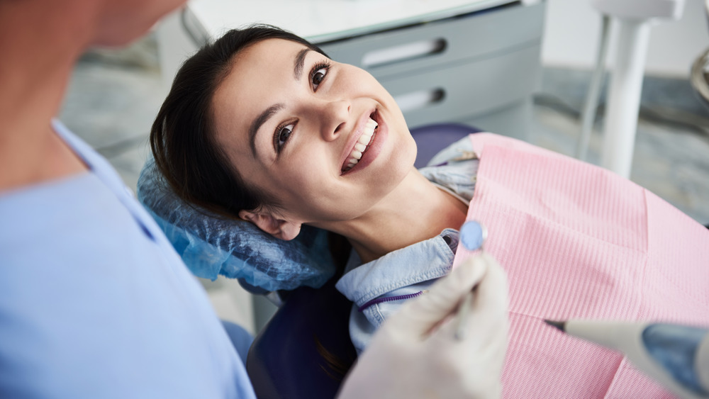 Woman in a dentist chair smiling at her dentist