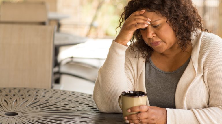 Sad woman stares into coffee mug