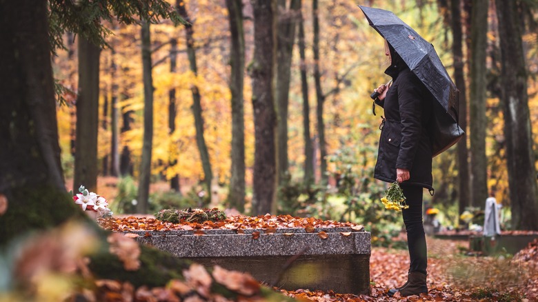 standing in cemetery with umbrella