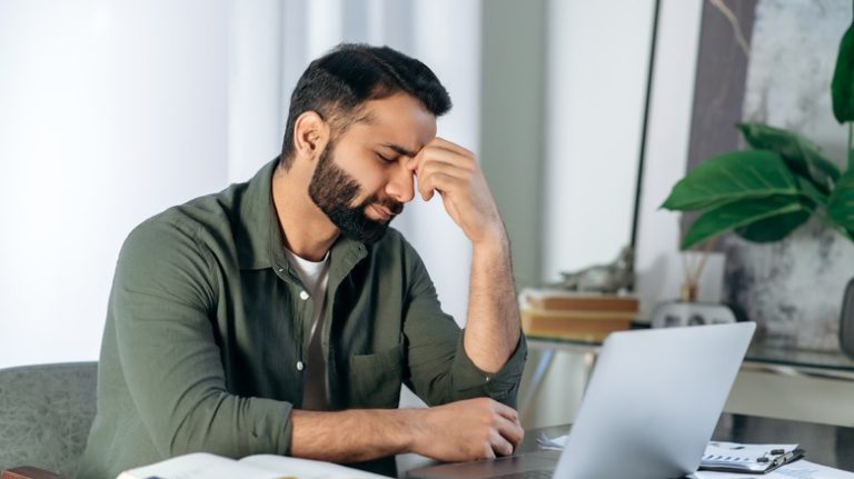 An anxious man sitting with a laptop