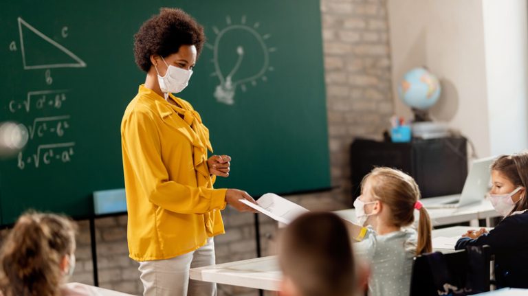 Teacher and children with masks in classroom