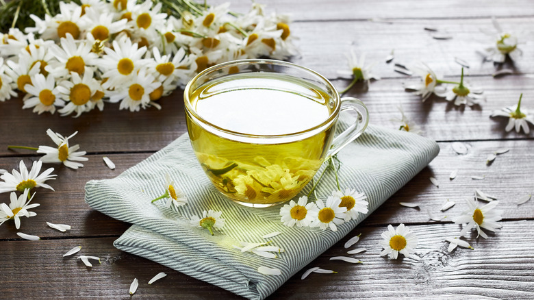 cup of chamomile tea surrounded by flowers