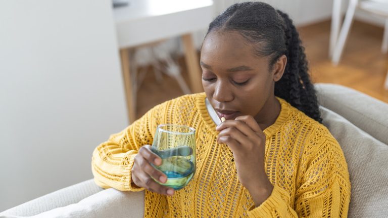 Woman taking pill with water