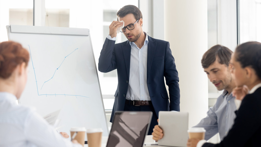 Man wiping sweat off his forehead during a presentation