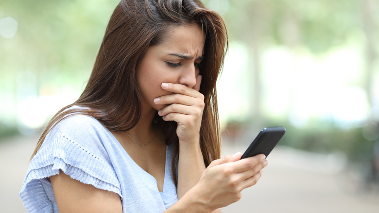 woman upset while looking at her phone