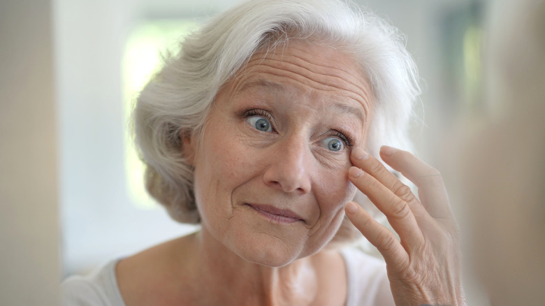 Older woman examining face in mirror