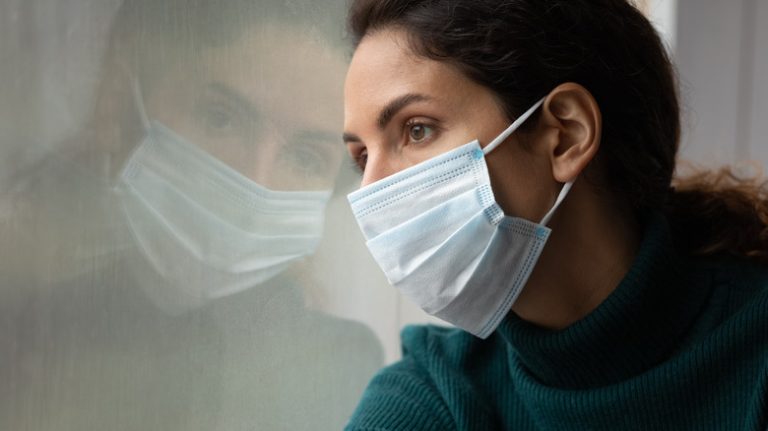 masked woman looking out window