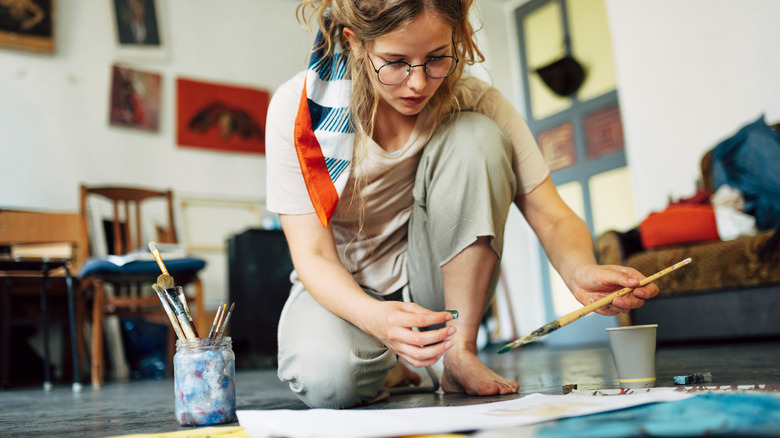 woman painting while sitting on floor