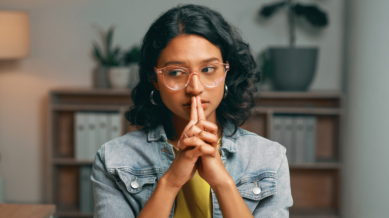 Worried woman with fingers on lips