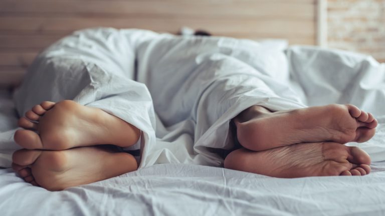 Couple's feet facing away in bed